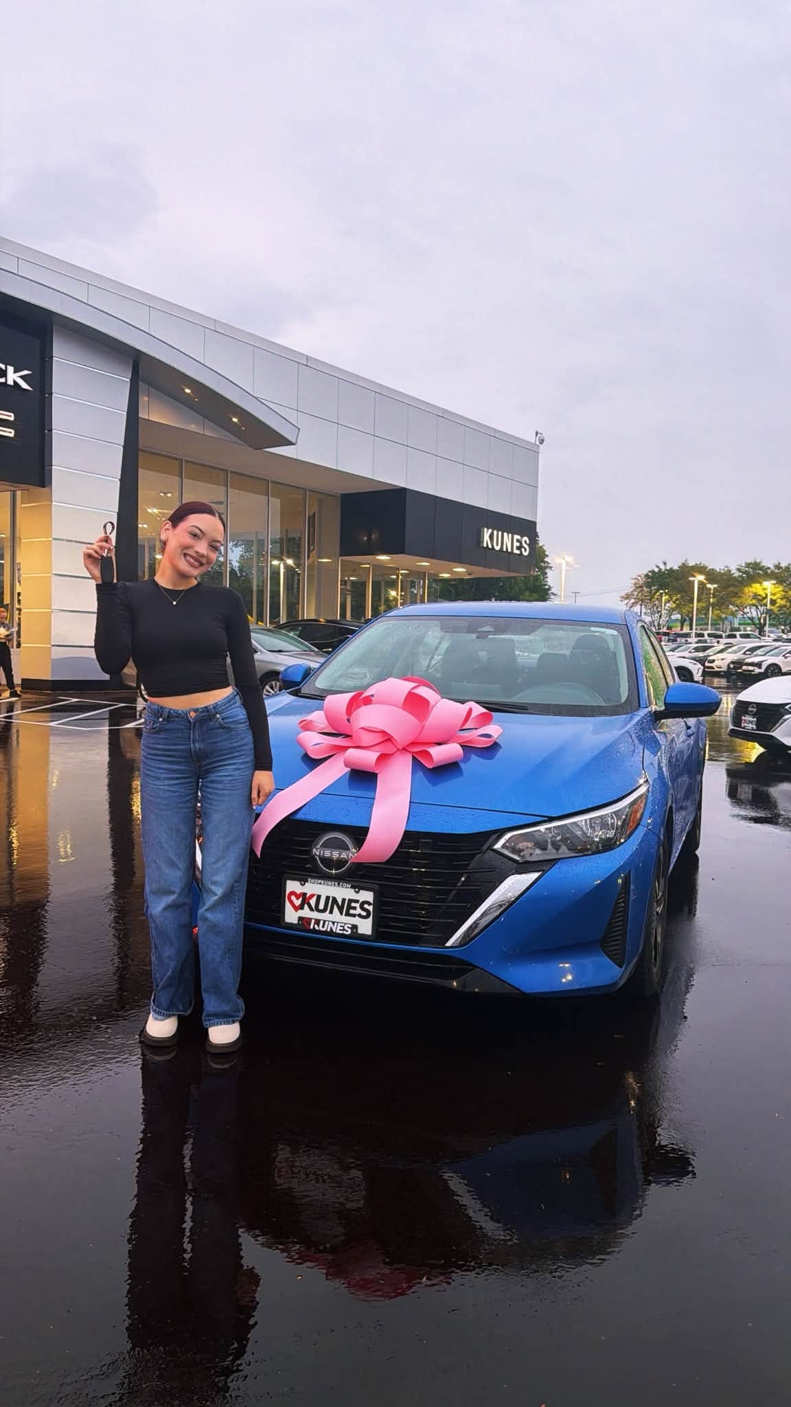 Customer posing with her new blue car with pink bow